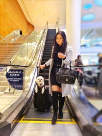 Woman standing on escalator in illuminated tunnel