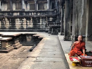 Full length of senior man sitting outside building