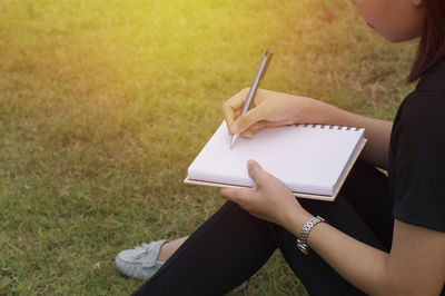 Close-up of woman writing in book