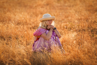 Woman wearing hat while sitting on field