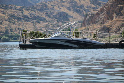 Boat moored on sea against mountains