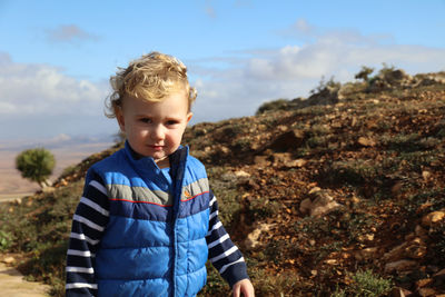 Portrait of boy standing against mountain