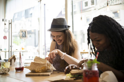 Friends sitting in cafe, eating sandwich