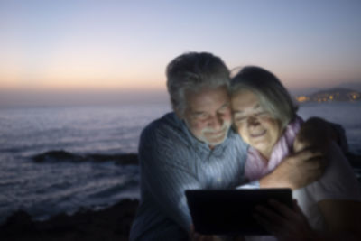 Friends looking at sea against sky during sunset