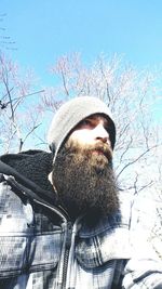 Low angle view of man wearing hat against sky during winter