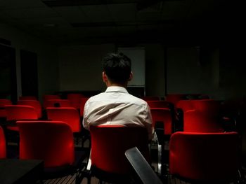 Rear view of man sitting on red chair