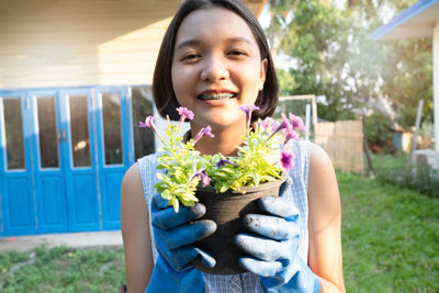 Portrait of smiling woman holding flowering plant