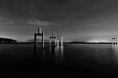 Wooden posts in lake against sky