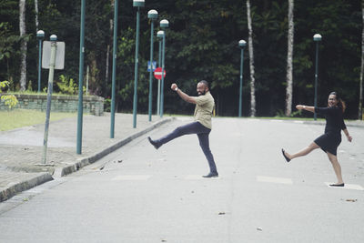 Full length of man jumping on road against trees