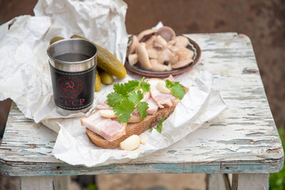 Lard with black bread,pickled cucumber for snack and glass of vodka, still life on peeling old stool