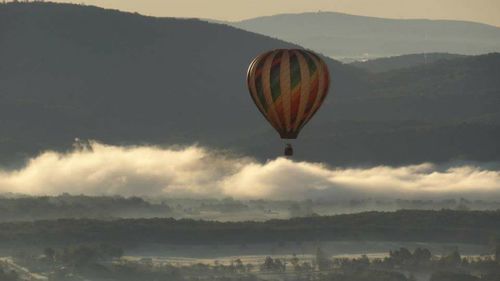 Hot air balloon flying over mountains against sky