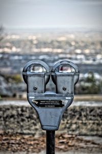 Close-up of coin-operated binoculars against cityscape