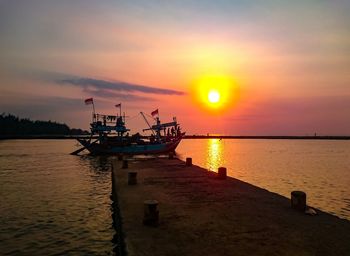 Fishing boat in sea against sky during sunset