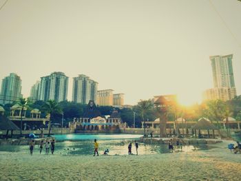 People playing on beach against clear sky