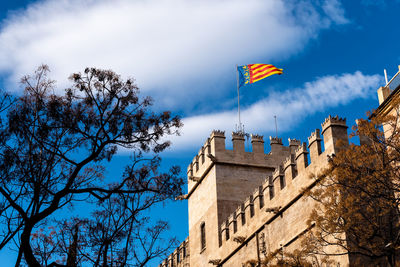 Low angle view of flag by building against sky