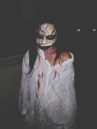 Portrait of woman in halloween make-up standing against black background