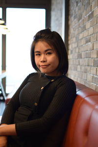 Portrait of young woman sitting on sofa in cafe