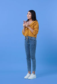Woman looking at camera while standing against blue sky