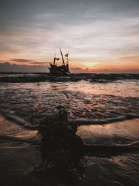 Silhouette ship in sea against sky during sunset
