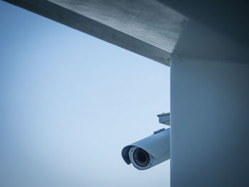 Low angle view of security camera against clear blue sky