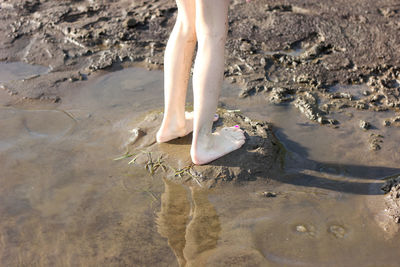 Girls feet stand in clear water on the beach