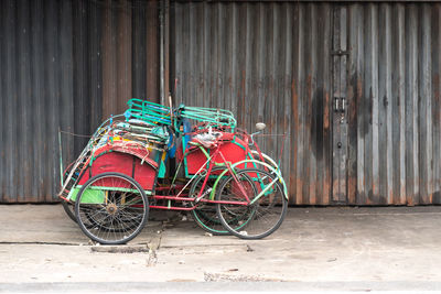 Trishaw or pedicab parked on street against wall