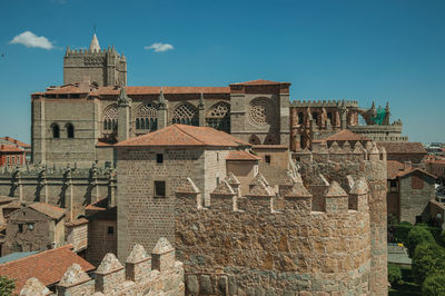 Pathway over stone wall with battlement around the town and side view of cathedral in avila, spain.