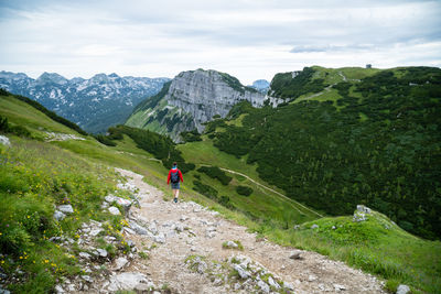 Rear view of man cycling on mountain against sky