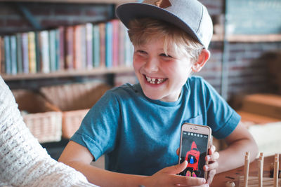 Portrait of boy holding mobile phone at home