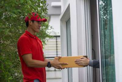 Young man delivering package to customer at doorway