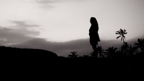 Silhouette man standing on rock against sky