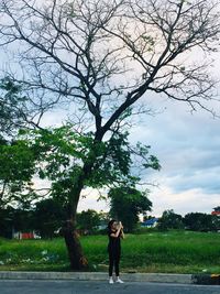 Woman standing by tree against sky