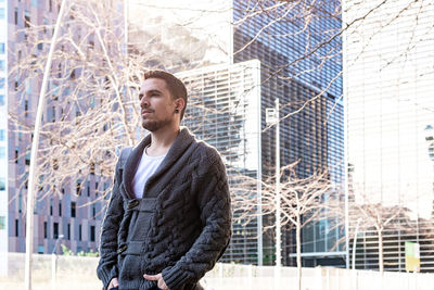 Young bearded man walking on the street next to office building