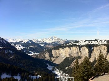 Scenic view of snowcapped mountains against blue sky