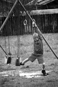 Full length of boy balancing on swing at playground