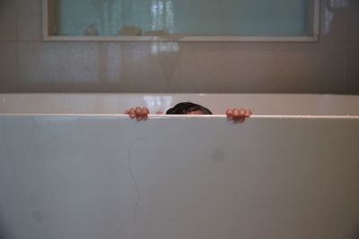 Cropped image of woman holding bathtub in bathroom