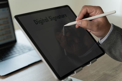 Midsection of woman using digital tablet on table