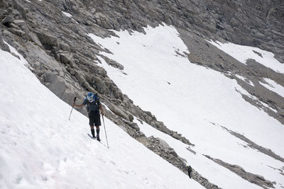 Rear view of man skiing on snowcapped mountain against sky