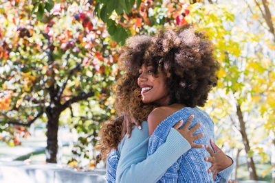 Two delighted happy female afro american friends hugging and smiling with love, giving warm hug