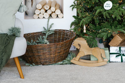 Stylish christmas decor, wicker basket with fir branches, gifts and a wooden toy horse