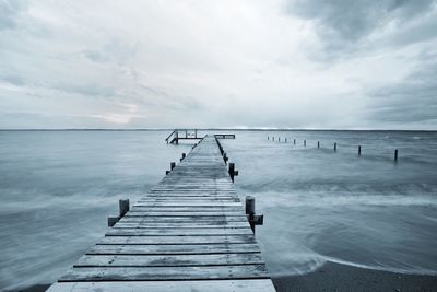 Pier over sea against cloudy sky