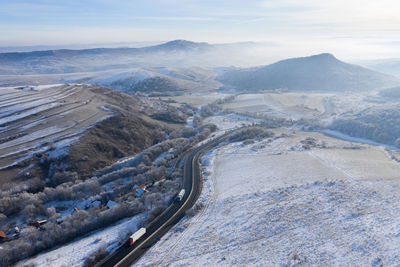 Aerial view of a winding road with trucks in a frozy winter sunny day