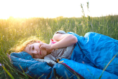 Cute girl in sleeping bag on field