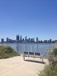 City by river and buildings against clear sky
