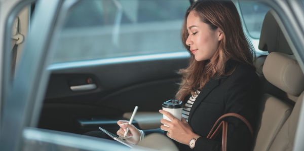 Woman using mobile phone in car