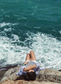 High angle view of woman relaxing on rock at beach