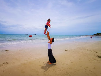 Mother throws her child into the air with joy on a beautiful beach