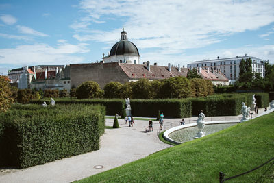 People in park by buildings against sky