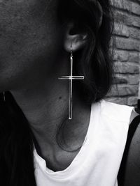 Close-up midsection of mid adult woman wearing cross shape earring