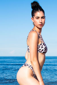 Portrait of woman in bikini standing at beach